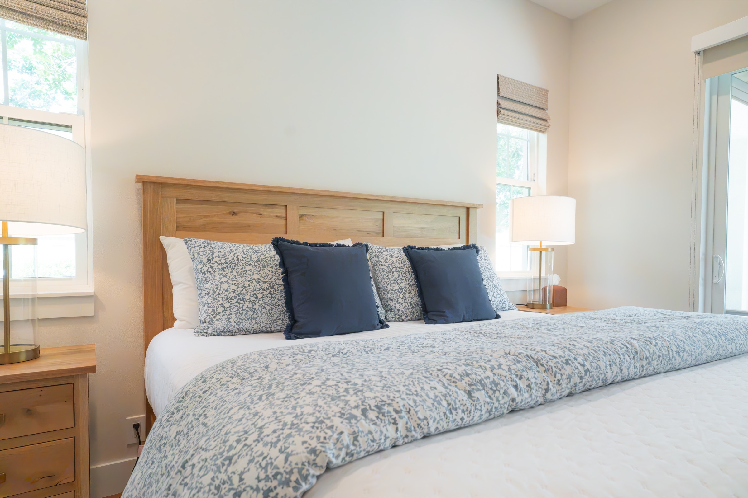 Fresh linens on a made bed by Refined Spaces